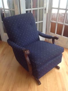 a blue chair sitting on top of a hard wood floor next to an open door