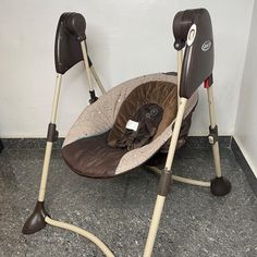 a baby swing that is sitting on the floor next to a wall with two handles