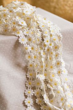 a white and yellow flowered scarf on top of a bed