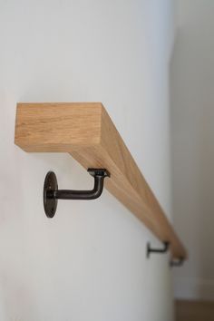 a wooden shelf mounted to the side of a wall with a metal hook on it