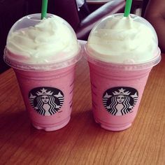 two starbucks drinks sitting on top of a wooden table