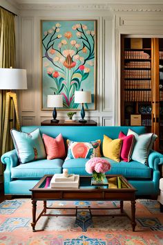 a living room with blue couches and colorful pillows on the coffee table in front of bookshelves