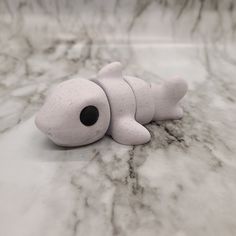 a small white toy laying on top of a marble counter