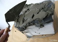 a person is holding a paintbrush near a piece of construction material that has been placed on top of it