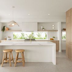 a kitchen with two stools in front of an island