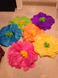 five different colored paper flowers on the floor