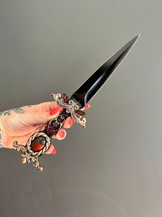 a person holding a knife with some sort of decoration on it