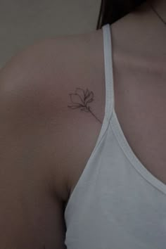 a woman's shoulder with a single flower tattoo on her left arm and chest