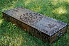 a wooden box sitting in the grass with an intricate design on it's lid