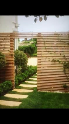 an outdoor area with grass, bushes and wooden slatted screens on the walls