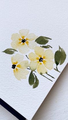 a card with yellow and green flowers painted on it's front side, sitting on a white surface