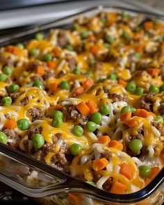 a casserole dish with peas, carrots and ground beef covered in cheese