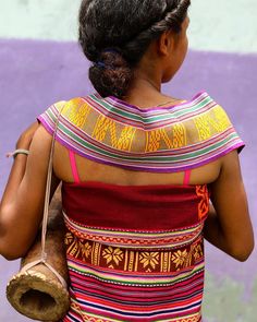 a woman in a colorful dress walking down the street with a handbag on her shoulder