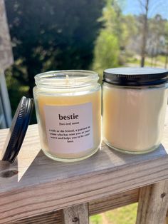 a candle with a label on it sitting on a wooden table next to a brush