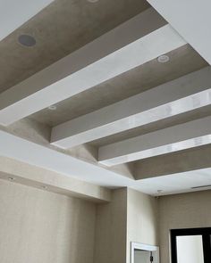 an empty room with white walls and ceiling tiles on the ceiling, in front of a mirror