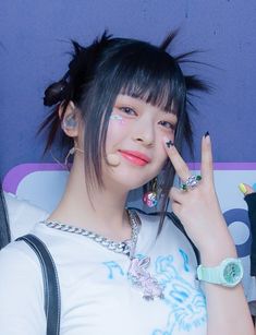 a girl with black hair and piercings holding her hand up in front of her face