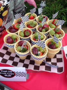 a table topped with cups filled with fruit on top of a checkered table cloth