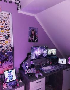 a desk with two computer monitors on top of it next to a wall covered in pictures