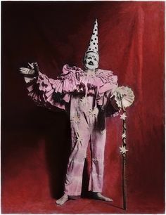 a creepy clown is holding a cane and wearing a pink suit with polka dots on it