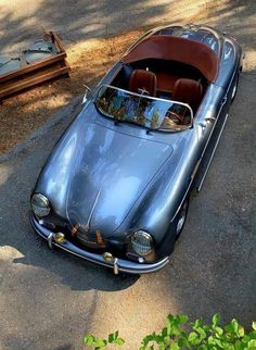 an old car is parked on the side of the road in front of some trees