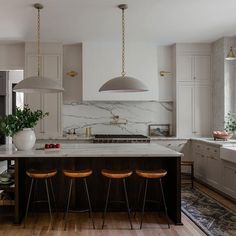 a kitchen with marble counter tops and wooden stools next to an island in the middle