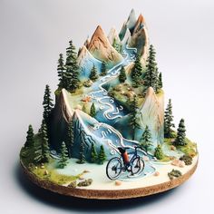 a mountain scene with a bicycle rider on the road and trees in the mountains around it