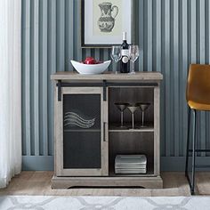 a wooden cabinet with wine glasses and plates on it in front of a striped wall