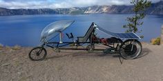 a solar powered bike parked on the side of a mountain overlooking a body of water