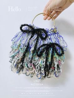 a hand is holding a small purse made out of different colored yarns and beads