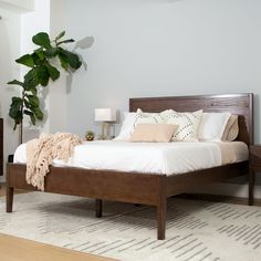 a bedroom with a bed, nightstands and a potted plant in the corner