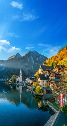 a small town on the shore of a lake with mountains in the background and blue sky