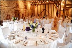 the tables are set with white linens and purple flowers