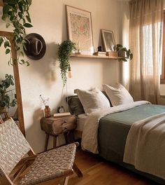 a bedroom with a bed, chair and plants on the wall next to it's windows