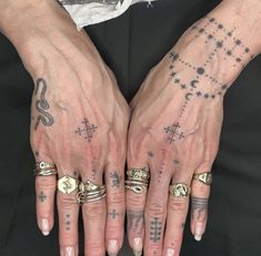 two hands with tattoos and rings on them