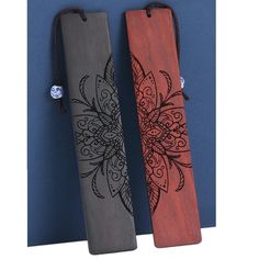 two wooden bookmarks with designs on them, one is red and the other is grey