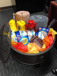 a basket filled with candy and snacks on top of a carpeted floor next to a fan