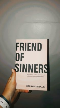 a person holding up a book that says friend of sinners