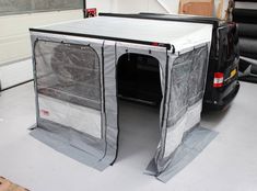 the back end of a van with its doors open in a storage area next to other vehicles