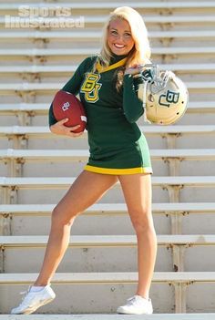 a female football player is holding a ball and posing for a photo in front of bleachers