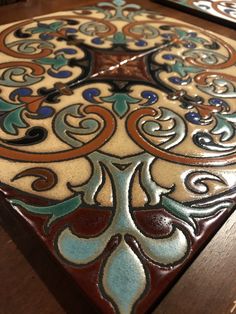 a wooden table topped with a colorfully painted tile design on it's surface