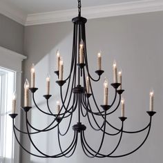 a black chandelier with candles hanging from it's sides in a room