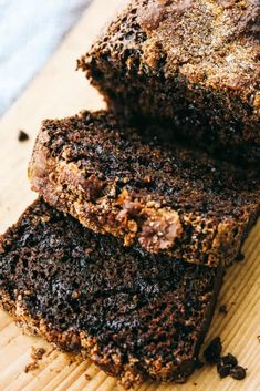 two pieces of chocolate cake sitting on top of a wooden cutting board