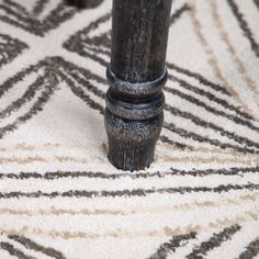 a close up of a wooden pole on a carpeted floor with white and black designs