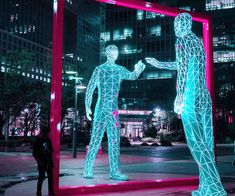 a couple of people standing in front of a large mirror with neon lights on it