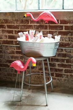 two flamingos are standing in front of a bucket filled with makeup and lotion