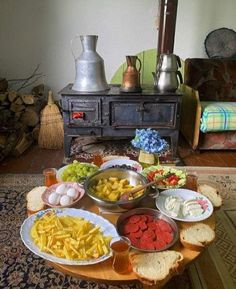 a table filled with different types of food on top of a wooden table next to an old stove