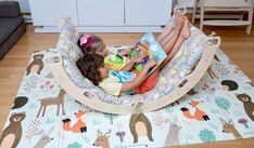 two children are laying in a swing bed reading books on the floor next to a couch