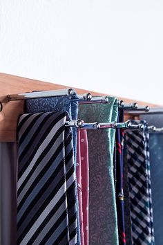 several different colored ties are hanging on a rack in front of a wall mounted coat rack