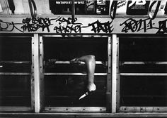 a man is hanging upside down on the door to a subway car that has graffiti all over it