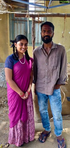 two people standing next to each other in front of a building